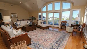 A spacious living room with a large window, wooden furniture, and a decorative rug. - Sea & Ease - Enjoy superb ocean views and great beach access from this home w/Private Pool! (Southern Shores)