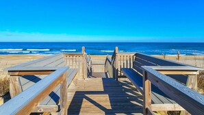 Een houten looppad dat naar een strand leidt, met heldere lucht.