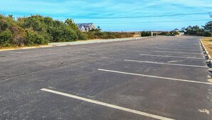 Un estacionamiento amplio y vacío, con espacios claramente delimitados y algunos edificios al fondo.