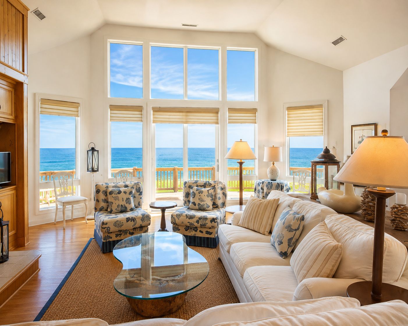 A spacious living room with a large window overlooking the sea, furnished with a sofa, chairs, and a coffee table.