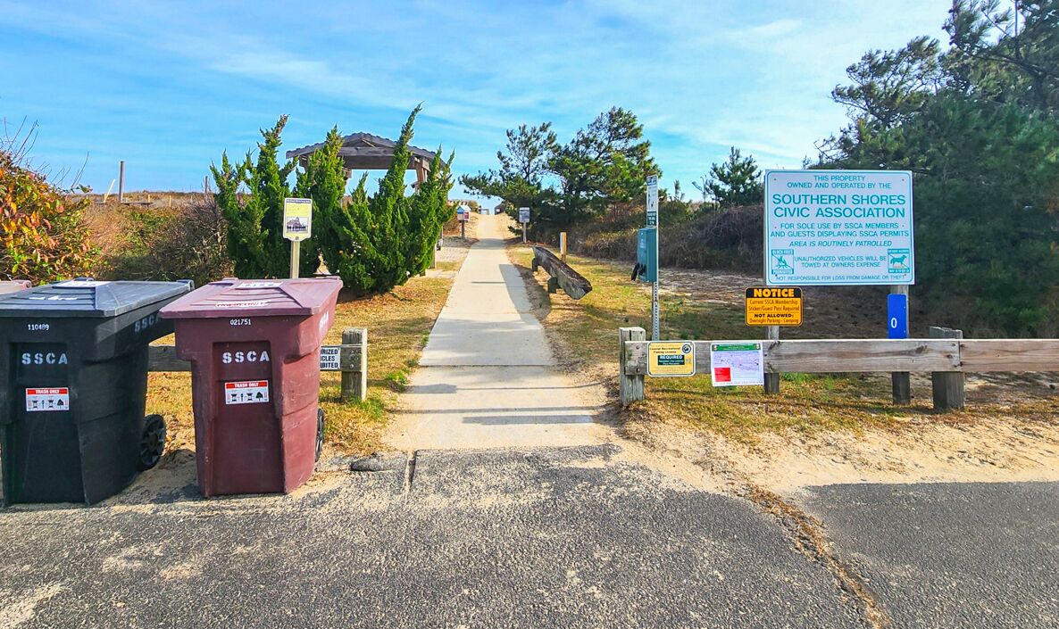 A pathway leading to a gazebo, with trash bins labeled 'SSCA' and a sign for the Southern Shores Civic Association.