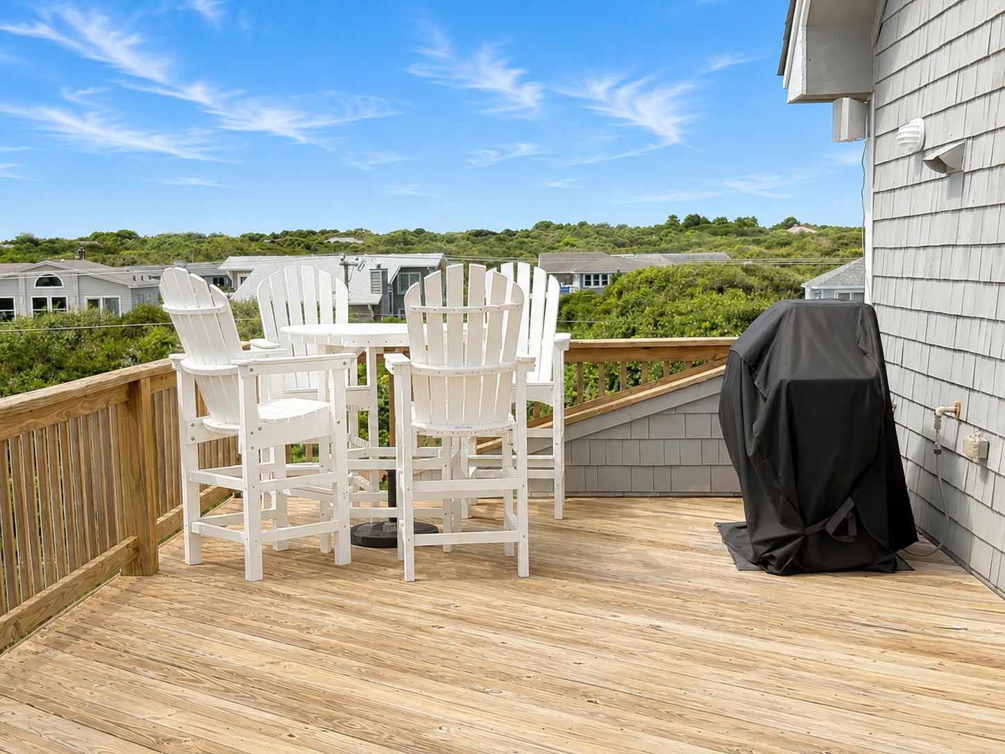 A wooden deck with outdoor furniture and a grill.