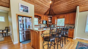 A spacious kitchen with wooden cabinets, a granite countertop, and a central island with bar stools.