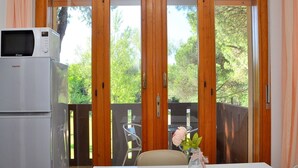 A dining area with a white table, a microwave, and a vase with a flower. - Comfort Near sea and Pinewoods (San Michele al Tagliamento)