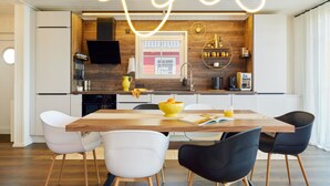 Une cuisine moderne avec un mur d’accent en bois, un four encastré et un coin repas comprenant une table et des chaises en bois.