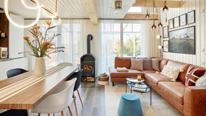 Un salon chaleureux avec une cheminée, un canapé, une table basse et un coin repas comprenant des chaises et une table.