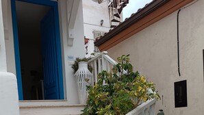 A white building with a blue door, white railing, and steps leading to a balcony. - Amazing Double Room N6784 in the Center (Tropea)