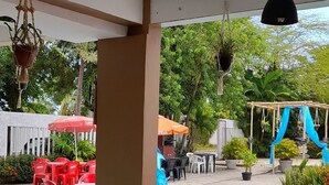A covered outdoor area with a pool, red and white chairs, and hanging plants. - Pousada Passarela do Caranquejo pb (Conde)