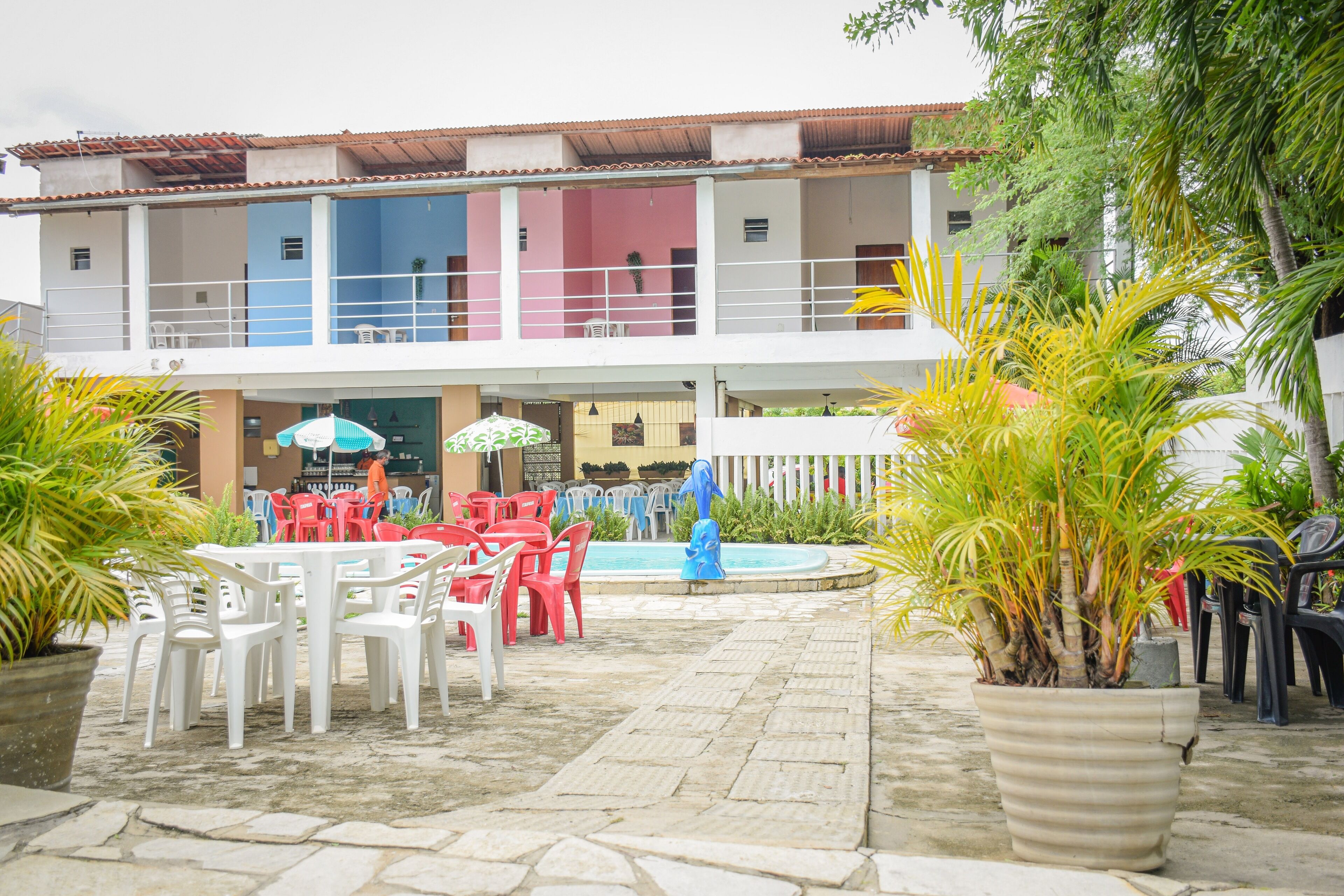 Un patio con mobiliario exterior, una piscina y un edificio con varios balcones.