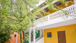A multi-story building with a yellow and white exterior, a balcony with a white railing, and a staircase leading to the upper floor. - Pousada Passarela do Caranquejo pb (Conde)