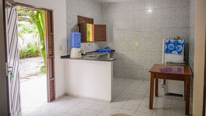 A compact kitchen with a built-in sink, a window with wooden shutters, and a small table. - Pousada Passarela do Caranquejo pb (Conde)