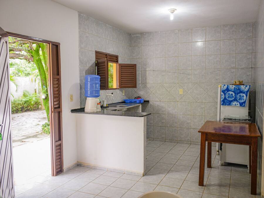 A compact kitchen with a built-in sink, a window with wooden shutters, and a small table.