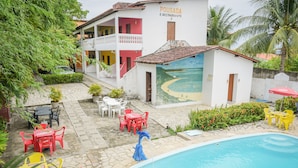 A pool area with a blue statue, outdoor seating, and a building with a mural. - Pousada Passarela do Caranquejo pb (Conde)