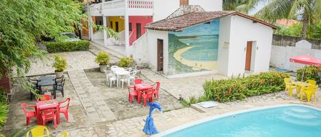 A pool area with a blue statue, outdoor seating, and a building with a mural.