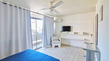 Een hotelkamer met een bed, een stoel, een televisie en een balkon.