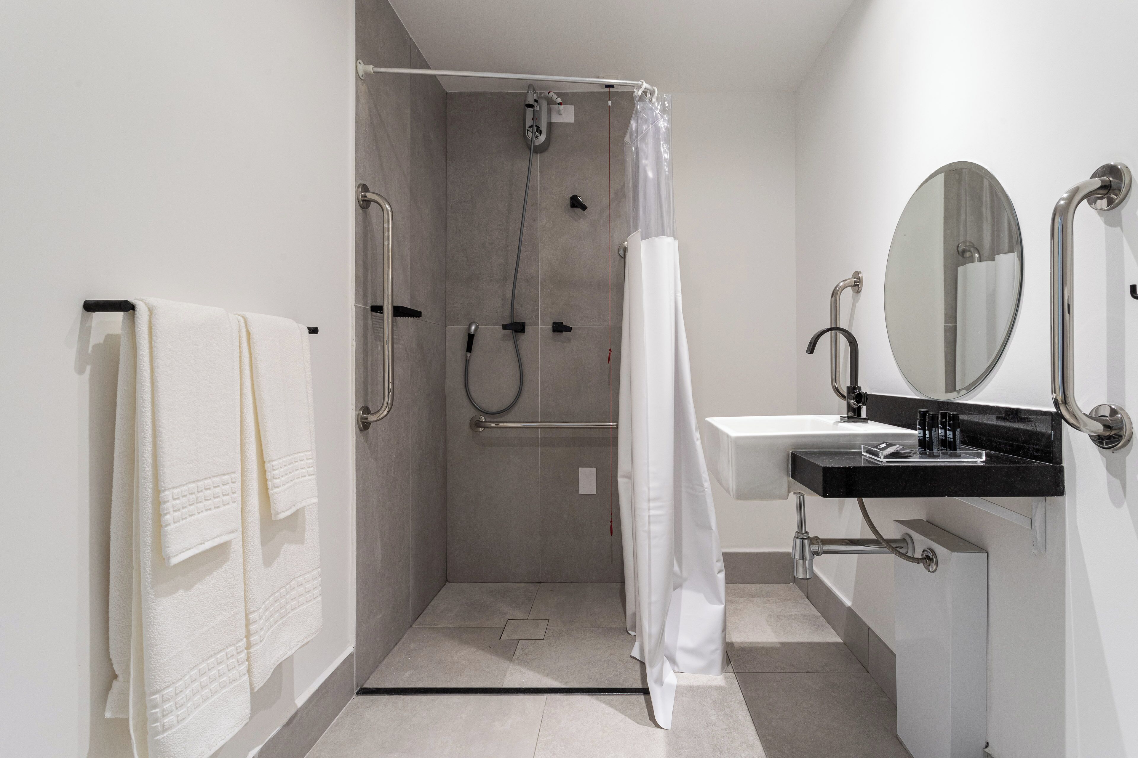 Un baño moderno con ducha, lavamanos y espejo.