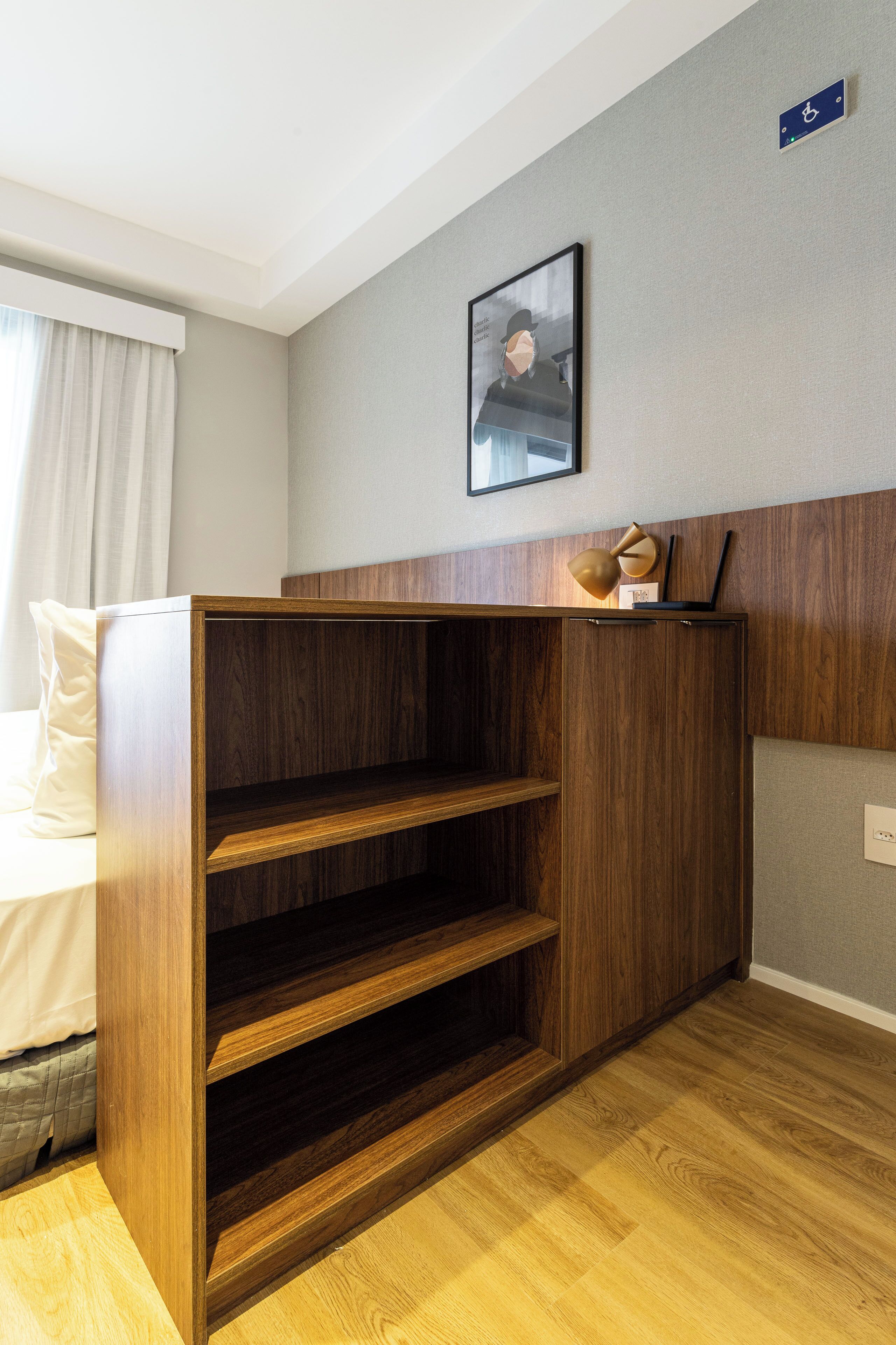 A hotel room with a wooden cabinet, a framed picture on the wall, and a wheelchair accessibility sign.