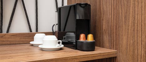 A wooden counter with a black coffee machine, two white cups, and two coffee cups.