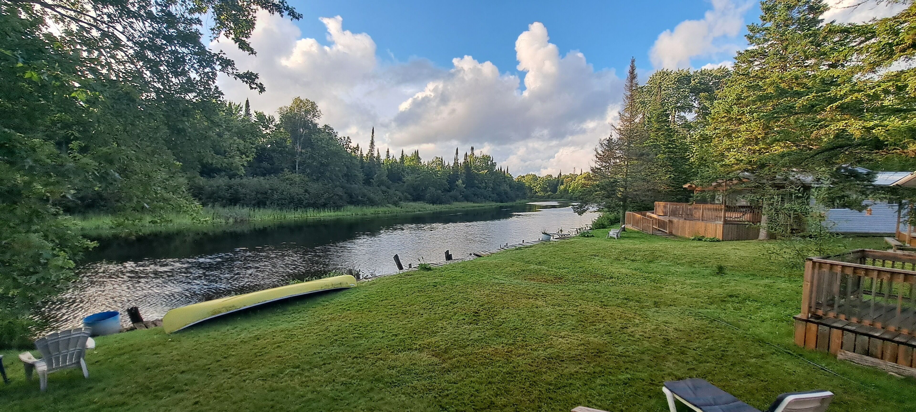 Un fiume con barche, una zona verdeggiante e un pontile di legno.