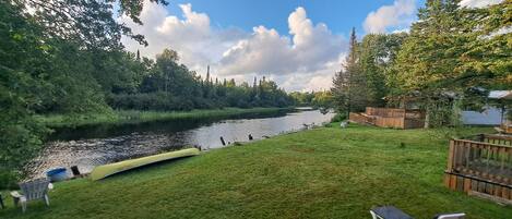 Un fiume con barche, una zona verdeggiante e un pontile di legno.