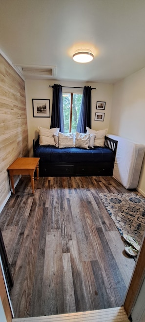 Une pièce chaleureuse avec un plancher en bois, un canapé bleu foncé, une petite table en bois et un tapis à motifs.