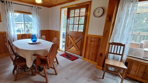 Un comedor acogedor con una mesa redonda, sillas de madera, un jarrón azul y una puerta de madera.
