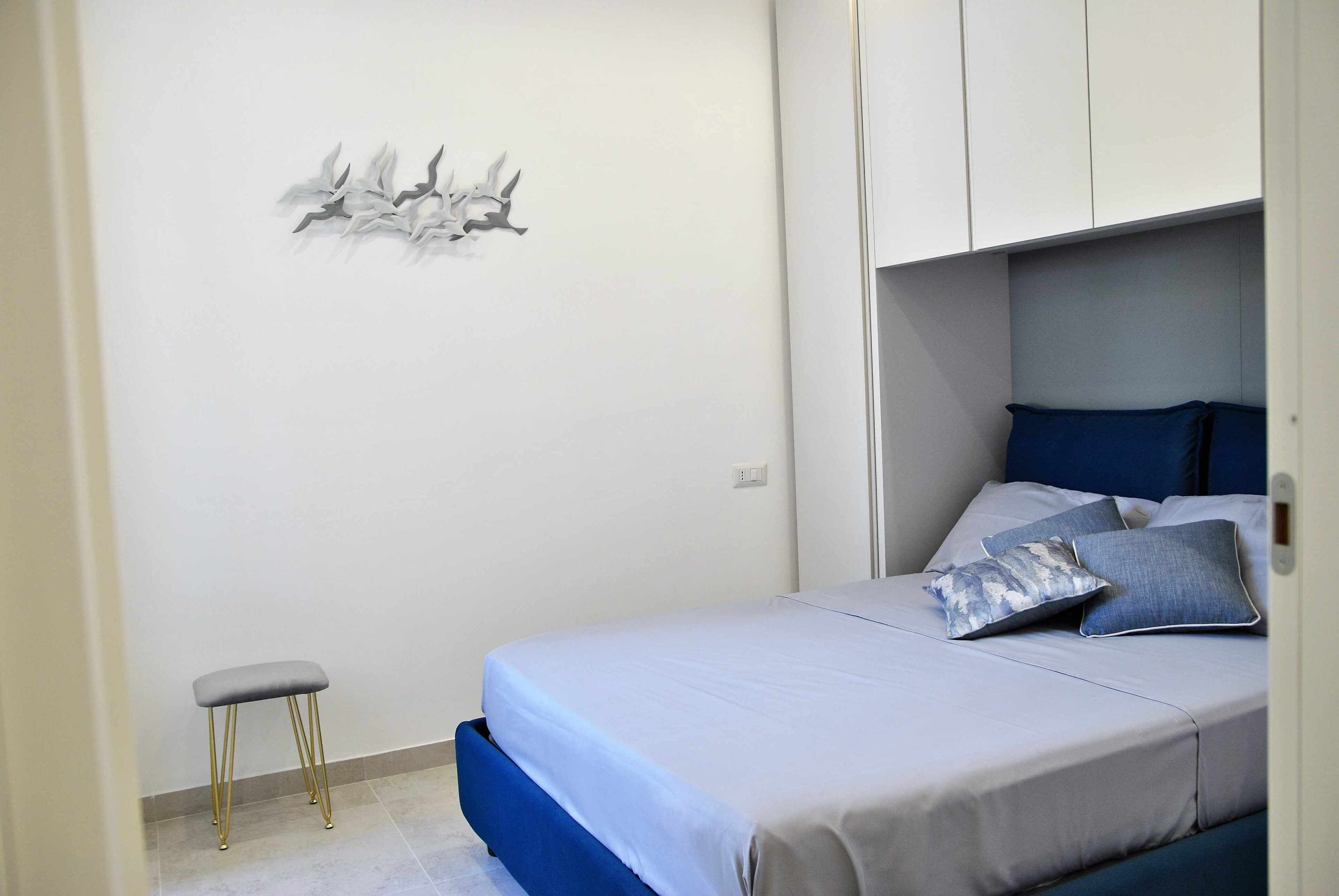 A bedroom with a bed, a small stool, and a wall decoration.