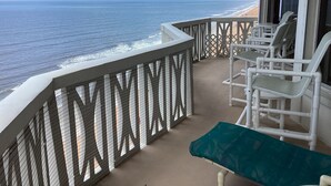 A balcony with a view of the ocean, white chairs, and a green cushion. - Oceanfront PENTHOUSE! Large Pool, Private Beach Access! Family Friendly!  (Ormond Beach)