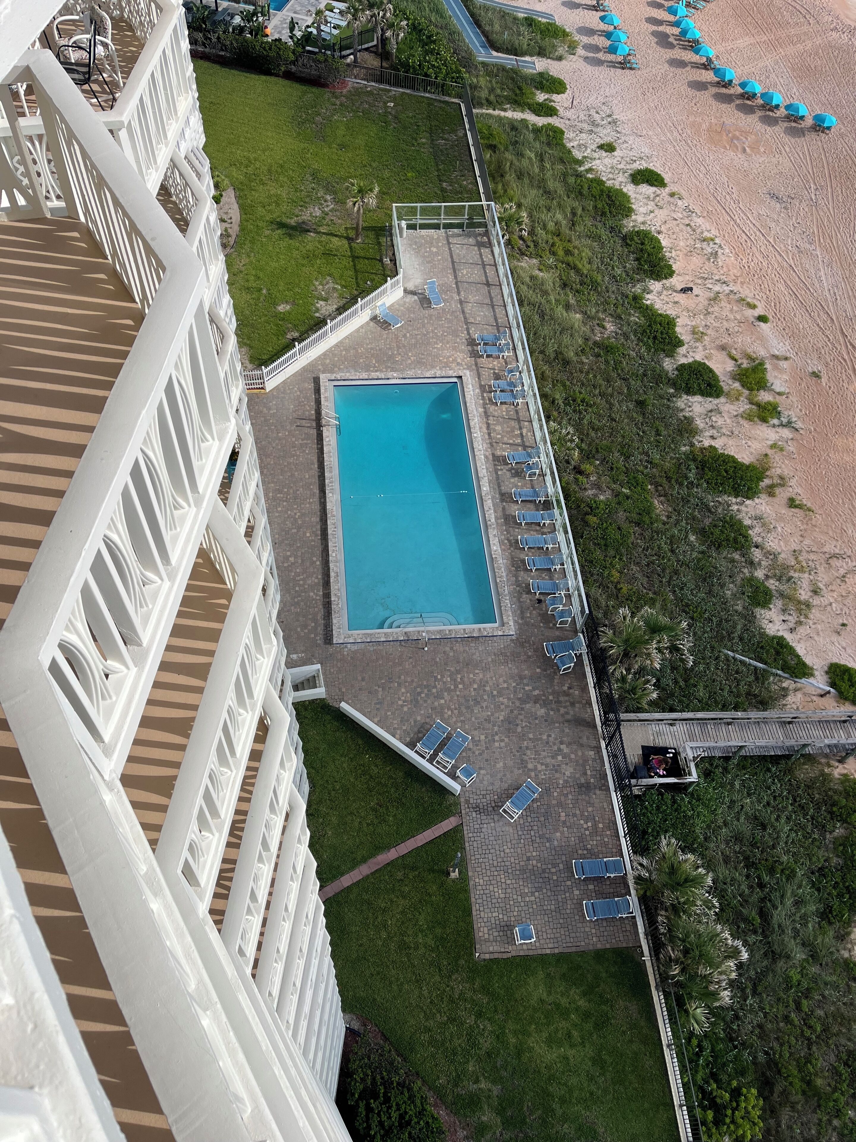 Vista aérea de un hotel con piscina rodeada de tumbonas, una terraza y una zona de playa.