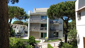 Un immeuble à plusieurs étages doté de balcons, d’une entrée sécurisée et entouré de verdure.