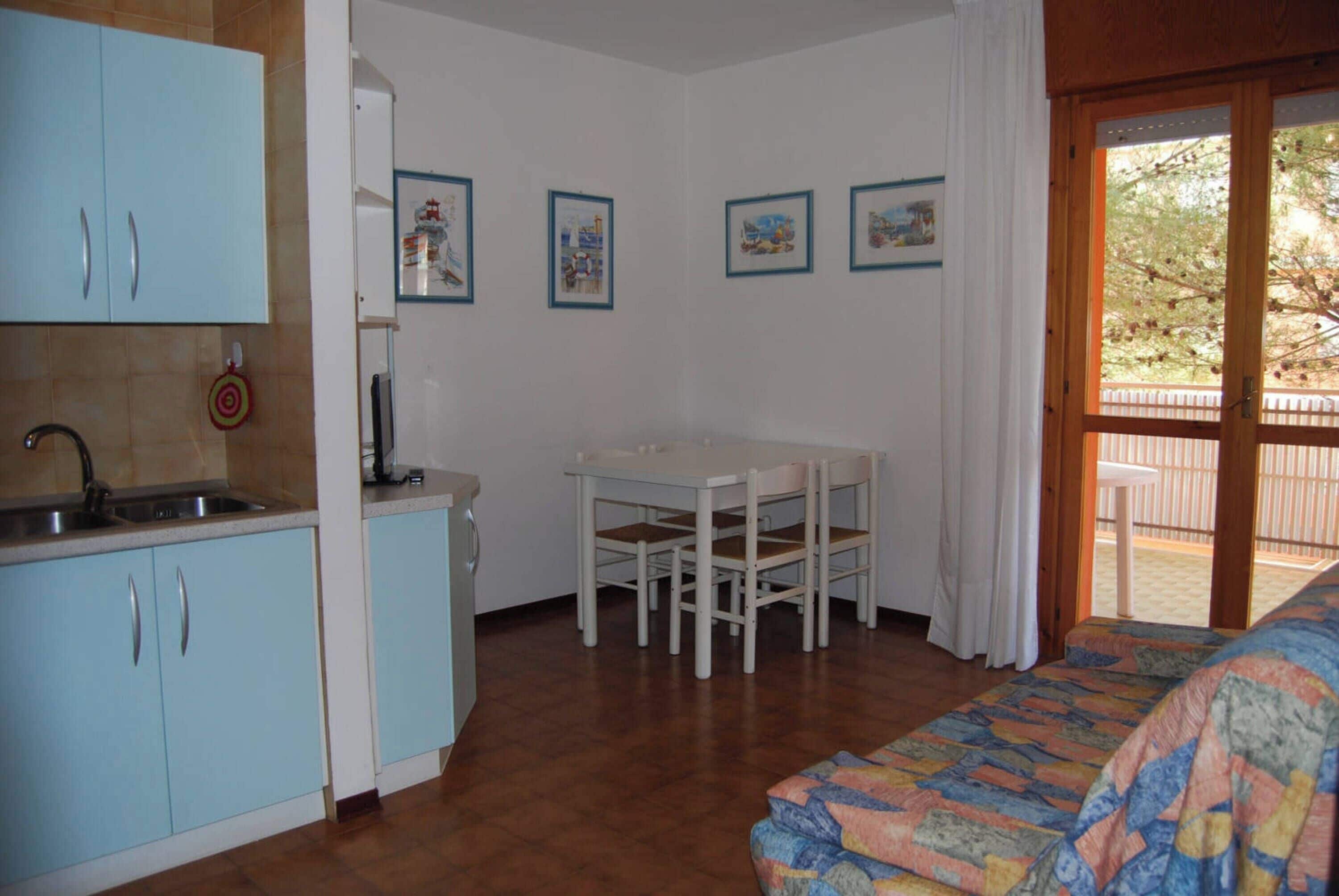 A compact room with a kitchenette, a dining table, and a bed.