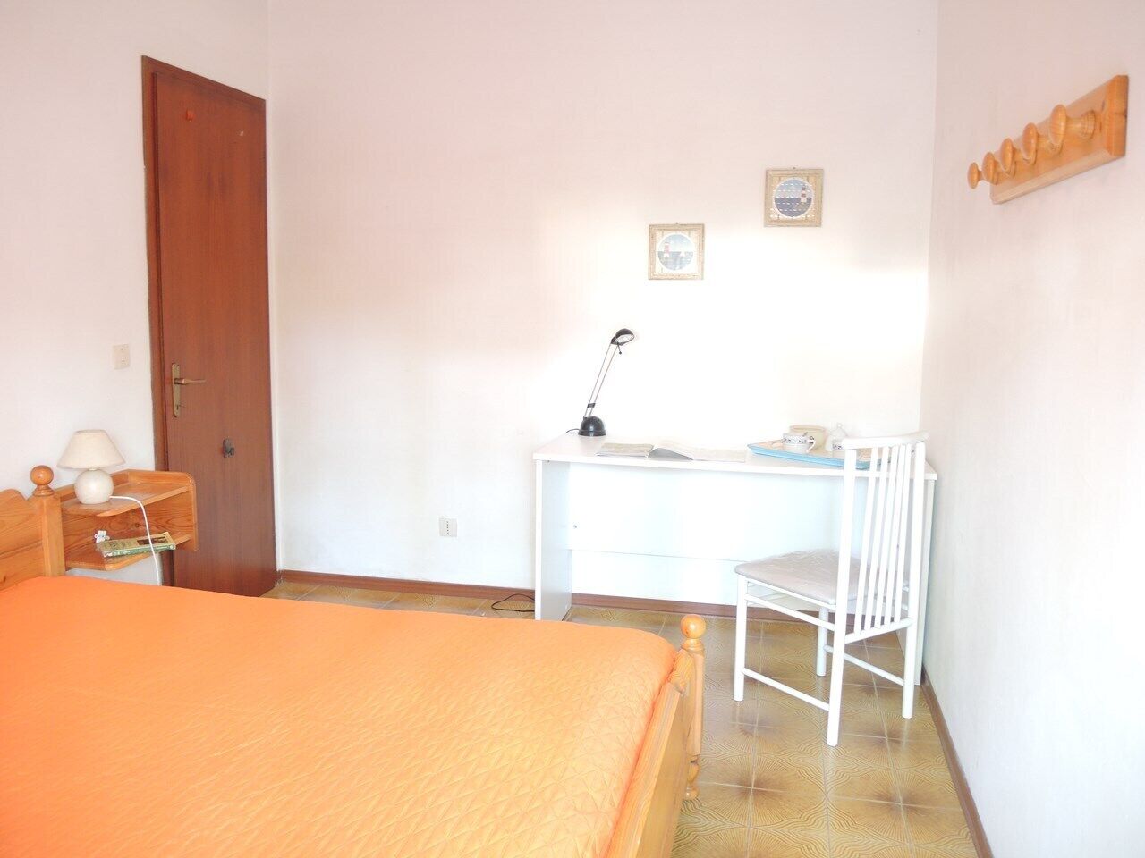 Un dormitorio con cama, escritorio, silla y puerta.