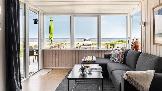 Sala de estar com vista para a praia, um sofá, uma mesa de centro e uma janela com vista para o mar.