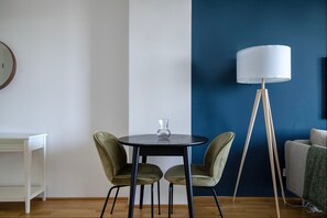 Een kamer met een ronde tafel, twee stoelen, een vloerlamp, een wit bureau en een blauwe accentmuur.
