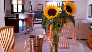 A dining area with a table set for two, a copper bucket, and a vase with sunflowers and candles. - Gabriel Villa Cyprus (Paralimni)