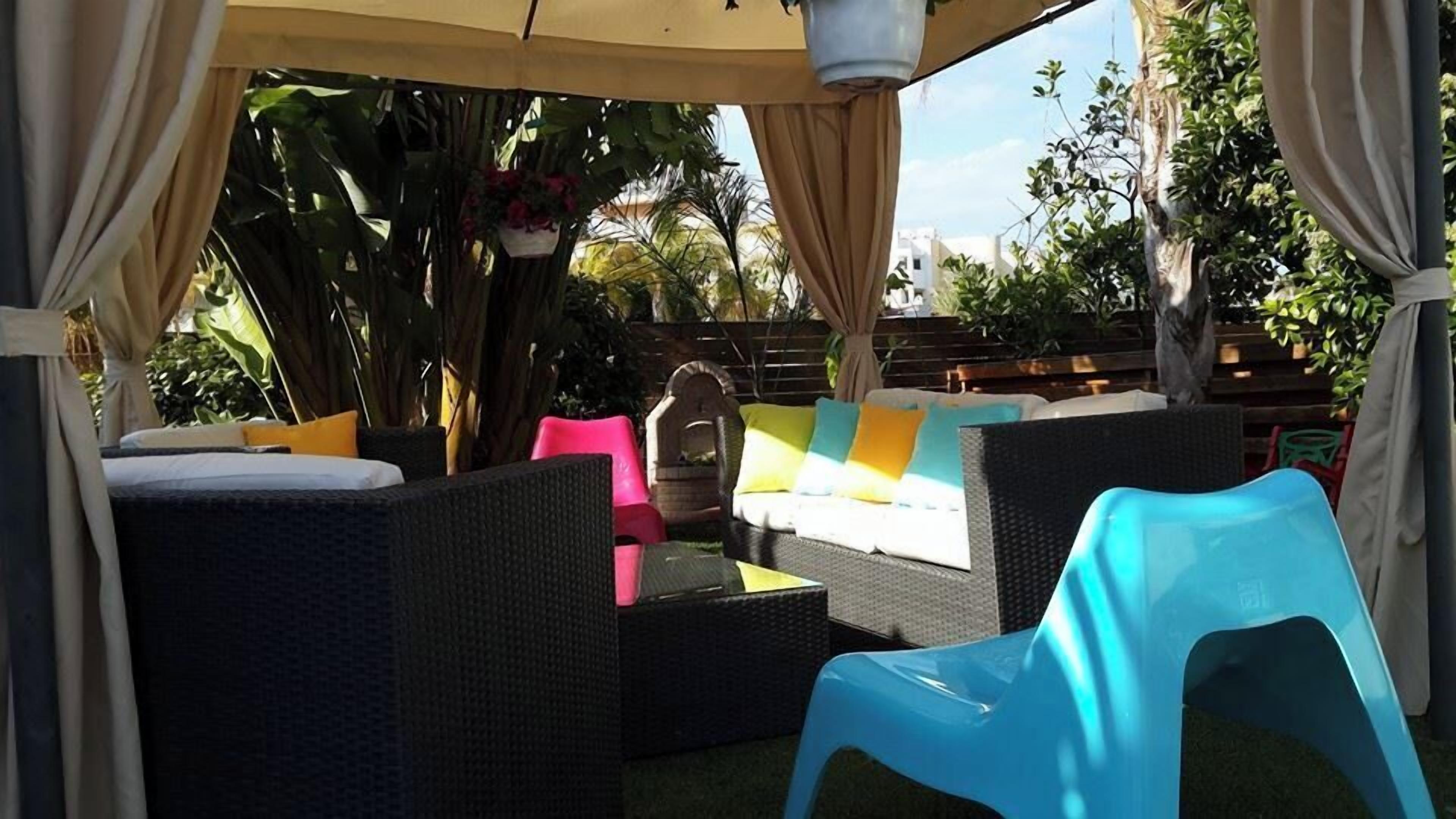 An outdoor seating area with wicker furniture, colorful cushions, and a canopy.