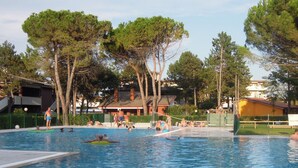 A swimming pool surrounded by trees and buildings. - Lovely Flat With Garden in a Residence-beahost (San Michele al Tagliamento)