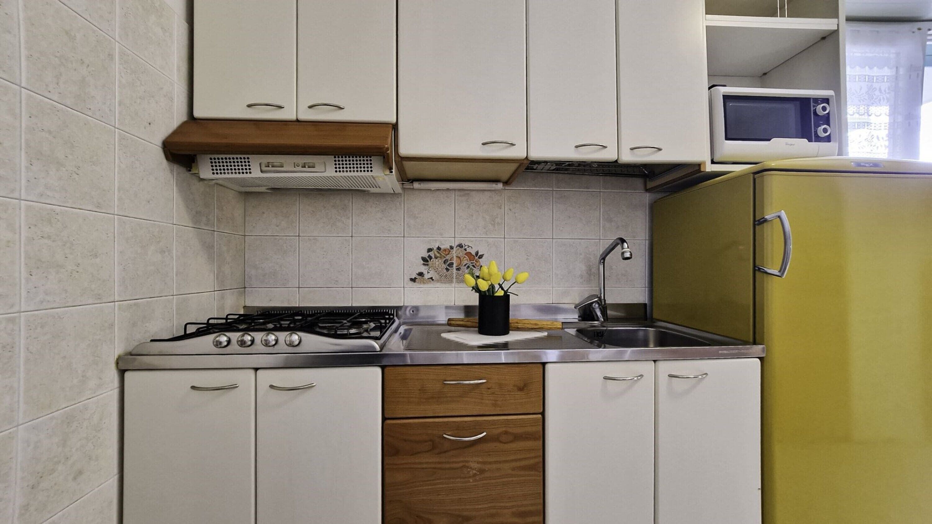Une cuisine de taille réduite équipée d’une cuisinière à gaz, d’un évier et d’un four à micro-ondes.