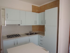 A kitchen with light blue cabinets, a gas stove, a sink, and a countertop. - Warm Apartment Near the Beach - Beahost (San Michele al Tagliamento)