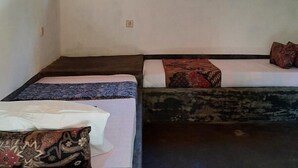 A room with two beds, a wooden door, and two paintings on the wall. - Rumah Nalu Surf Camp (South Krui)