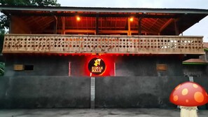 A building with a red sign that reads "RUMAH NALU" and a decorative fence.