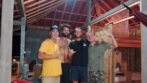 A group of four people posing indoors with a wooden ceiling and a bed in the background. - Rumah Nalu Surf Camp (South Krui)