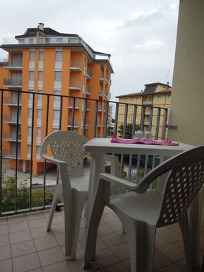 En balkon med et bord og stole, der udover et boligområde med farverige lejlighedskomplekser.