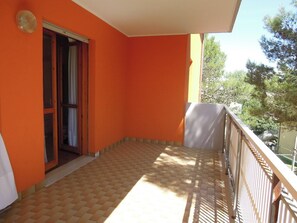 A balcony with a tiled floor, a door, and a railing.