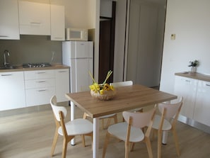 A modern kitchen with white cabinets, a microwave, a refrigerator, and a dining table with four chairs.