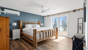 Ein Schlafzimmer mit einem hölzernen Bett, einem Nachttisch, einem Deckenventilator und Blick ins Freie.