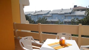 A balcony with a table and chairs, a white tablecloth, and a pitcher of orange beverage.