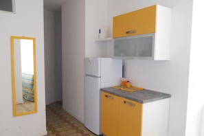 A compact kitchen with a refrigerator, a sink, and a countertop. - Bright Flat Next to the Beach-beahost (San Michele al Tagliamento)