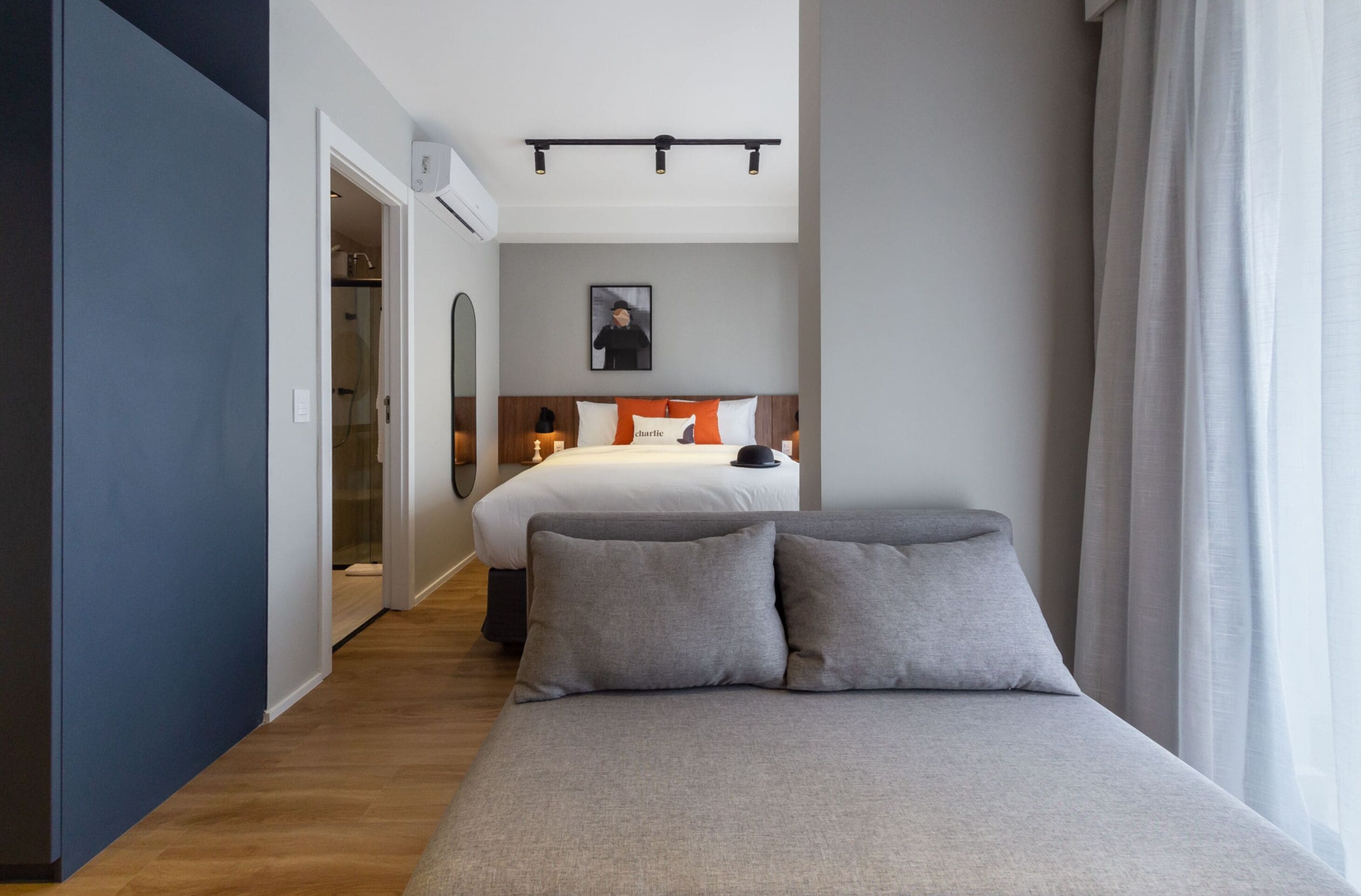 A modern hotel room with a large bed, a bedside table, a nightstand, and a wall-mounted light fixture.