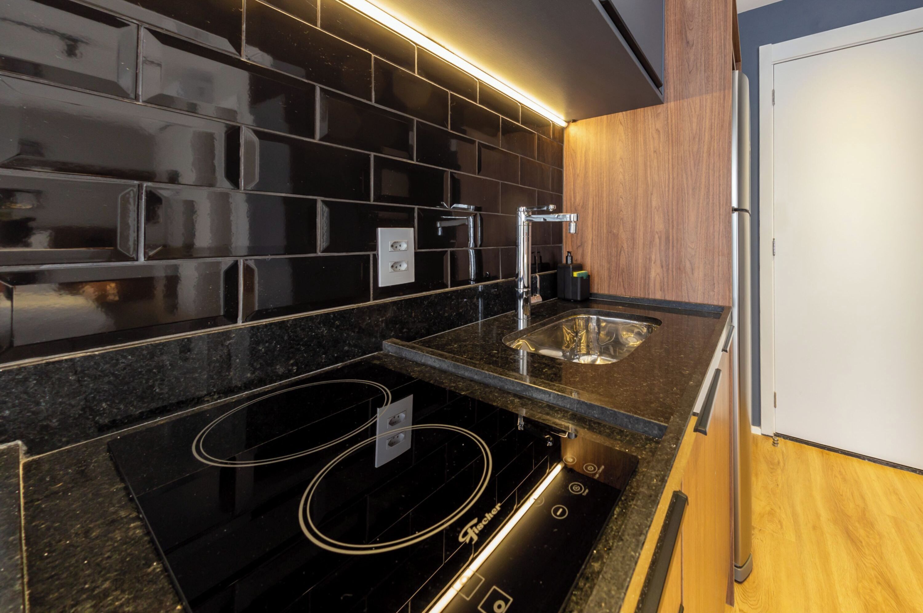 Una cucina moderna con zoccolo a mosaico nero, elettrodomestici in acciaio inossidabile e mobili in legno.